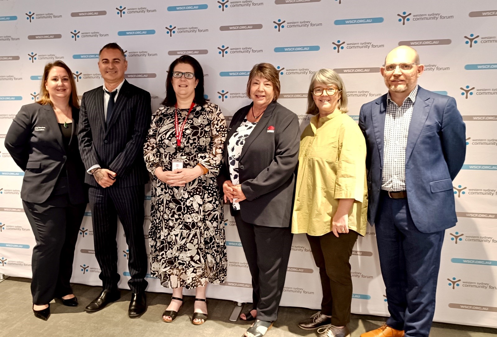 6 event hosts standing against a wall smiling.